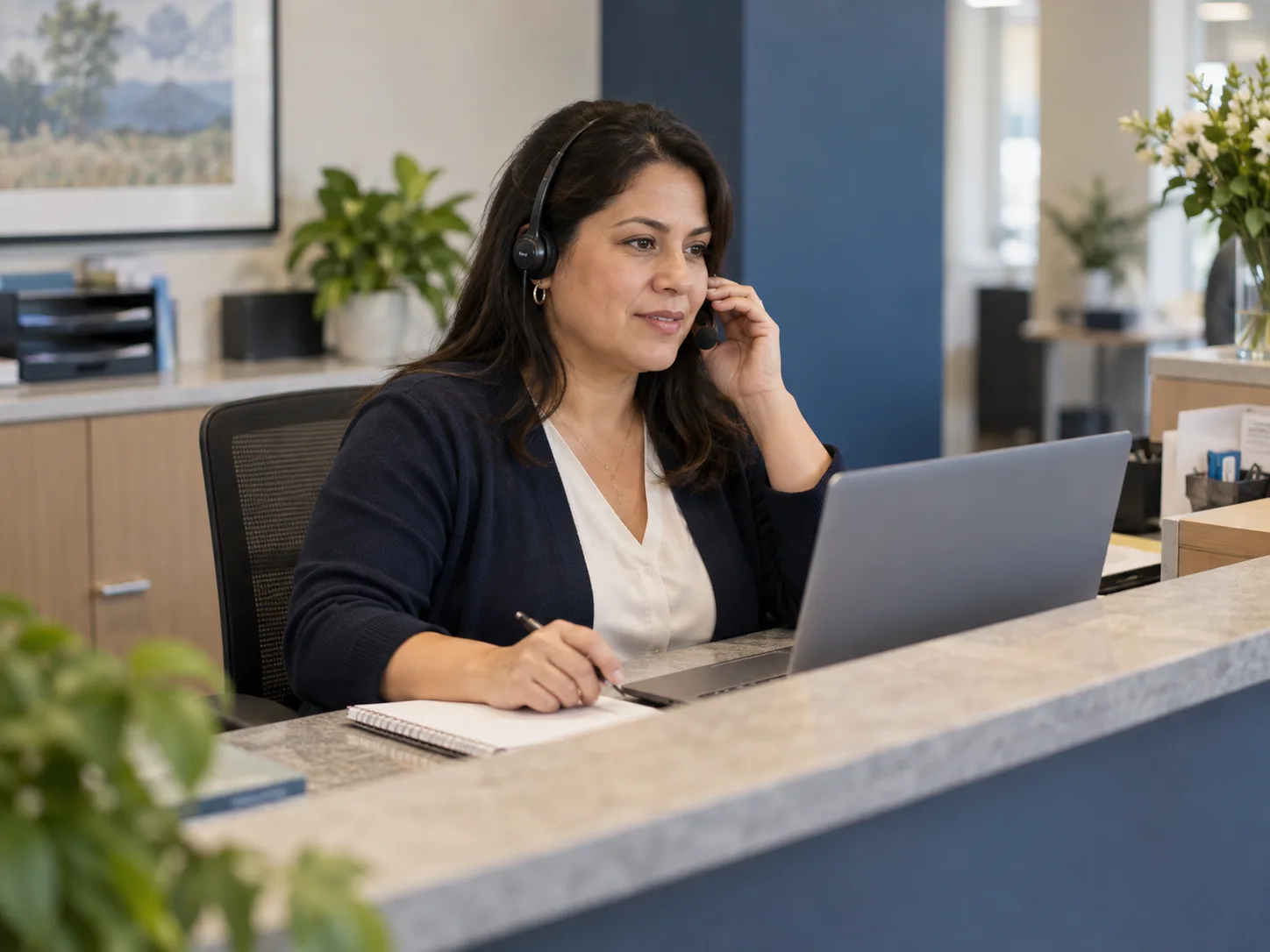 An administrative coordinator listening to a call with a headset and notebook